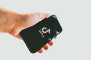 Photographie d'une main tenant un smartphone affichant le logo TikTok